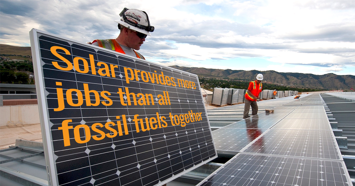 A solar installer holding a panel that says solar creates more jobs than any other kind of energy